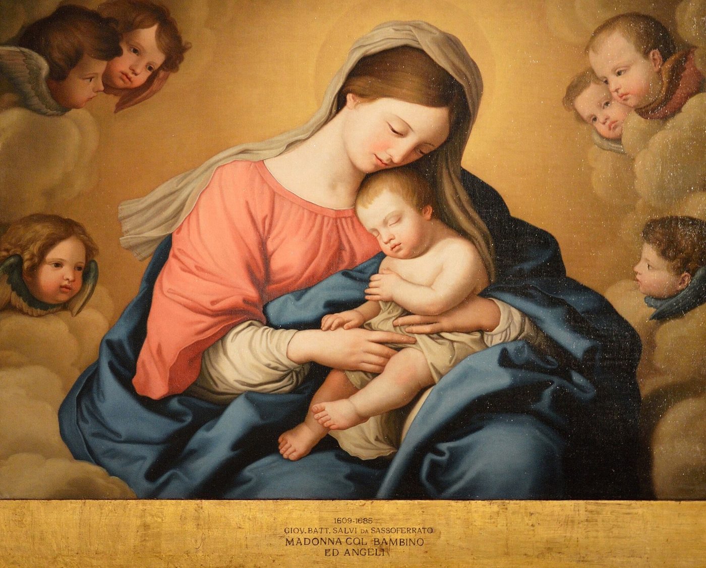 Baroque painting of Mary in a blue mantle cradling the sleeping child Jesus, with attending angels gathered close in soft light.